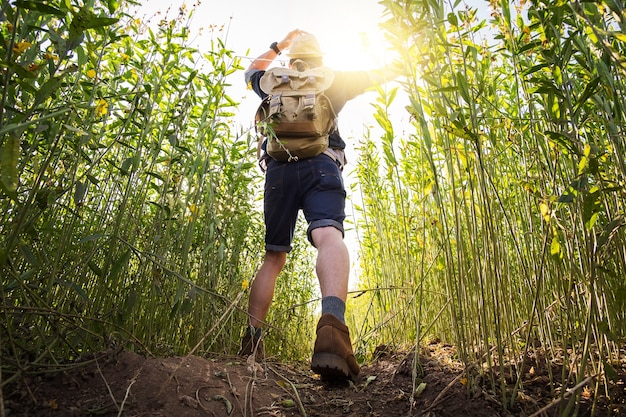 Young Man Traveller mit Rucksack entspannenden Outdoor mit felsigen Berge auf Hintergrund Sommer Urlaub und Lifestyle Wandern Konzept