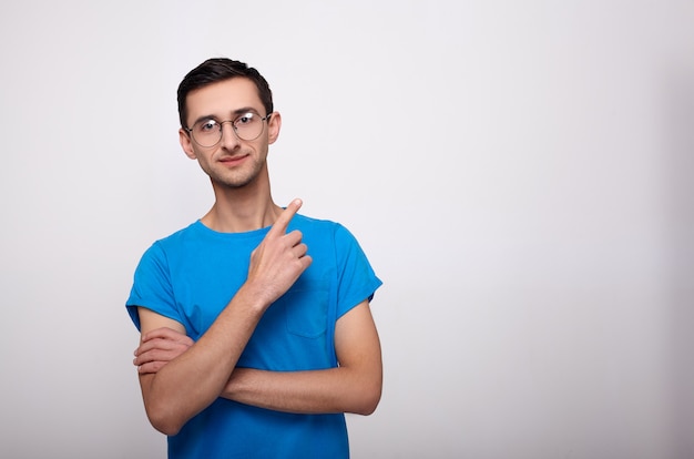 Young sorprendió al hombre con una camiseta azul apuntando a la derecha con el dedo.