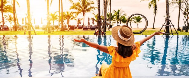 Foto young woman traveler relaxing and enjoying the sunset by a tropical resort pool while traveling for summer vacation