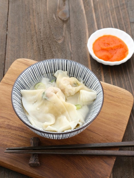 Yummy Wonton Soup Knödelsuppe oder Pangsit Kuah serviert in Schüssel auf grauem Tisch selektiver Fokus