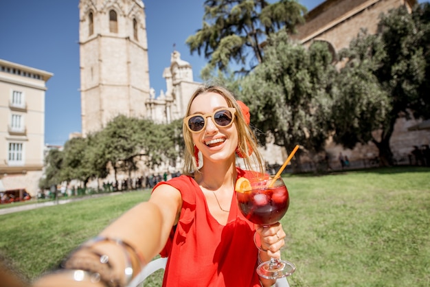 Yuong-Frau macht Selfie-Foto mit Sangria, traditionellem spanischen Alkoholgetränk, draußen in der Altstadt von Valencia sitzend