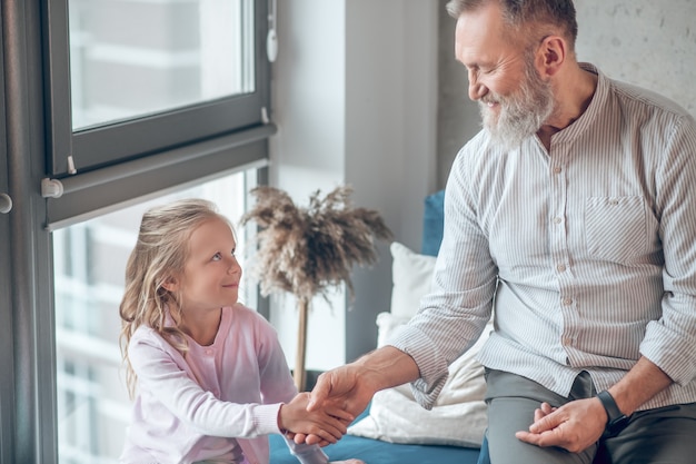 Zärtlichkeit. Ein kleines süßes Mädchen, das glücklich aussieht, Zeit mit ihrem Vater zu verbringen