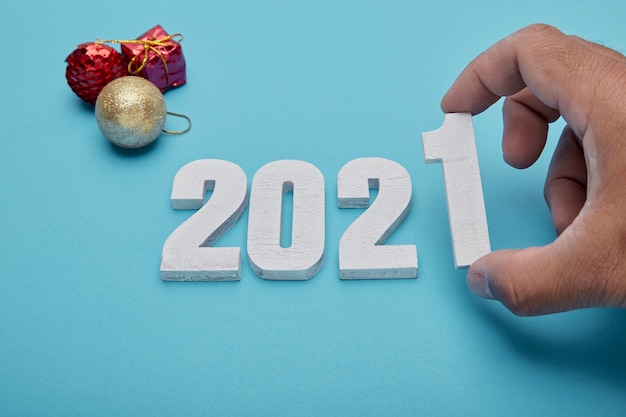 Zahlen 2021 und Hand auf pastellblauem Hintergrund für Neujahr