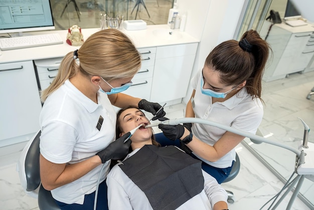 Foto zahnärzte behandeln die zähne einer jungen patientin mit der neuesten ausrüstung zahnmedizin zahnmedizin zahnarztassistentin