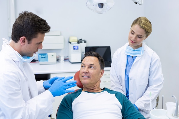 Zahnärzte, die mit einem männlichen Patienten interagieren