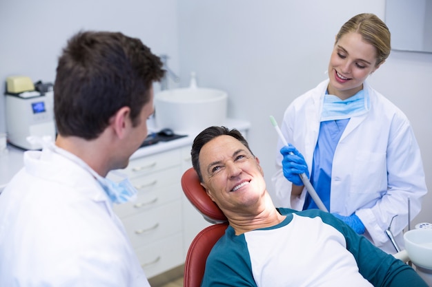 Zahnärzte, die mit einem männlichen Patienten interagieren