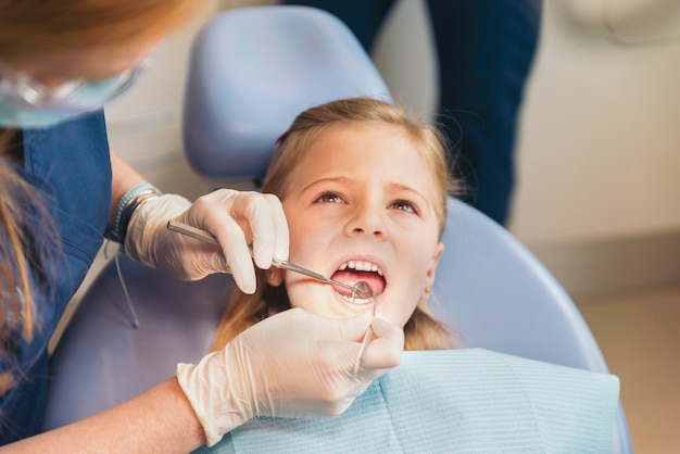 Zahnärzte mit einem Patienten während eines zahnärztlichen Eingriffs an Mädchen. Zahnarztkonzept