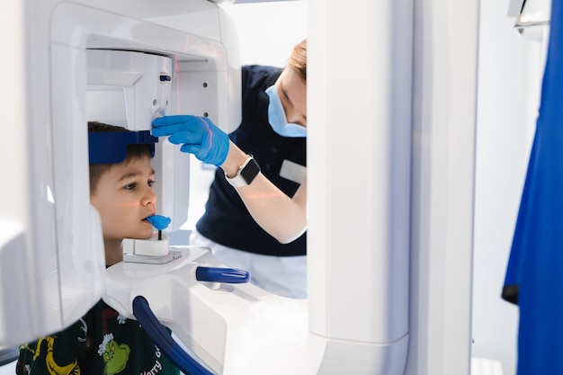 Zahnärztin, die einem kleinen Jungen mit einem modernen Röntgengerät eine Panorama-Zahnröntgenaufnahme macht
