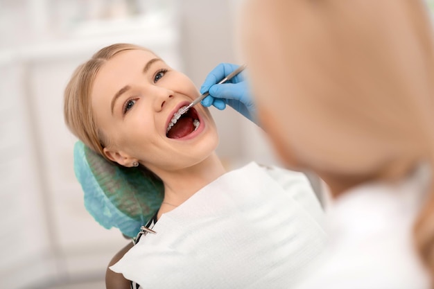 Zahnärztin, die Zahnspangen ihrer fröhlichen Patientin überprüft