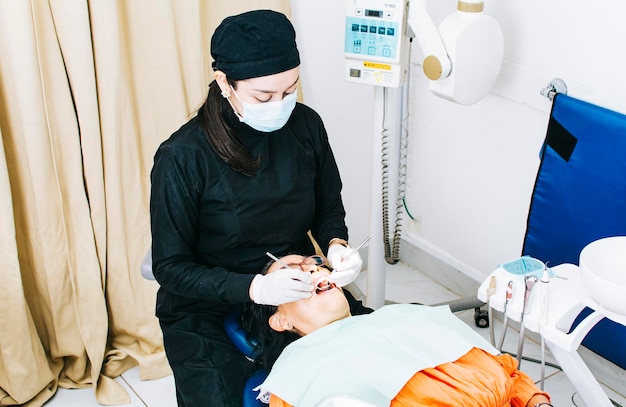 Zahnärztin mit liegendem Patienten Zahnarzt untersucht den Mund des Patienten Zahnärztin tut Endodontie für Patientin Zahnarzt, der Stomatologie durchführt