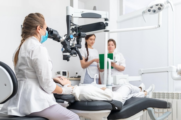 Zahnärztin mit Zahnmikroskop, die Patientenzähne im Büro der Zahnklinik behandelt