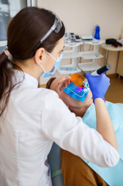 Zahnärztin untersucht den Patienten mit Instrumenten in der Zahnklinik. Der Arzt führt eine Zahnbehandlung an den Zähnen einer Person im Zahnarztstuhl durch. Selektiver Fokus
