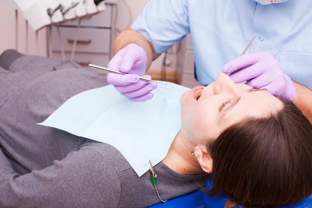 Zahnarzt behandelt Zähne mit Hilfe von zahnärztlichen Instrumenten. Schwangere Patientin
