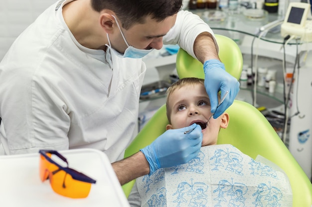 Zahnarzt, der die Zähne des kleinen Jungen in der Klinik untersucht Zahnproblem