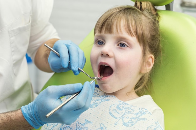 Zahnarzt, der die Zähne des kleinen Mädchens in der Klinik untersucht Zahnproblem