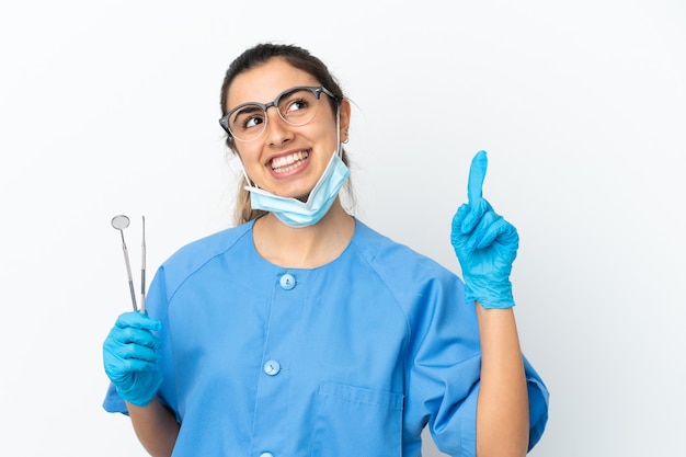Zahnarzt der jungen Frau, die Werkzeuge lokalisiert auf weißer Wand hält, zeigt eine große Idee auf