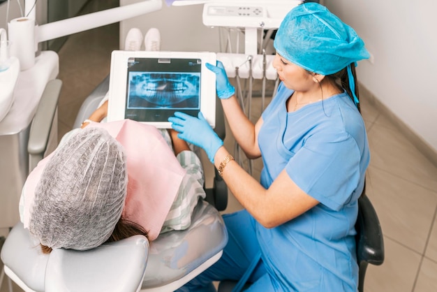 Zahnarzt, der mit einem Patienten spricht, während er ein Röntgenbild in einer Zahnklinik zeigt