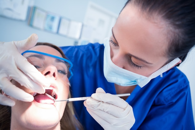 Zahnarzt, der Patientenzähne im Zahnarztstuhl überprüft
