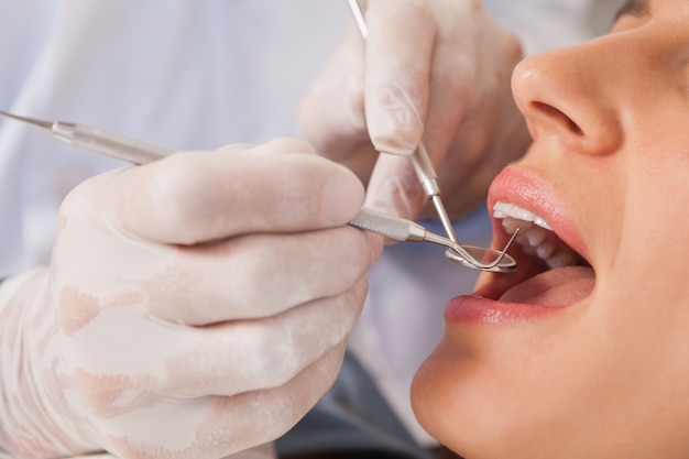 Zahnarzt, der Patientenzähne im Zahnarztstuhl überprüft