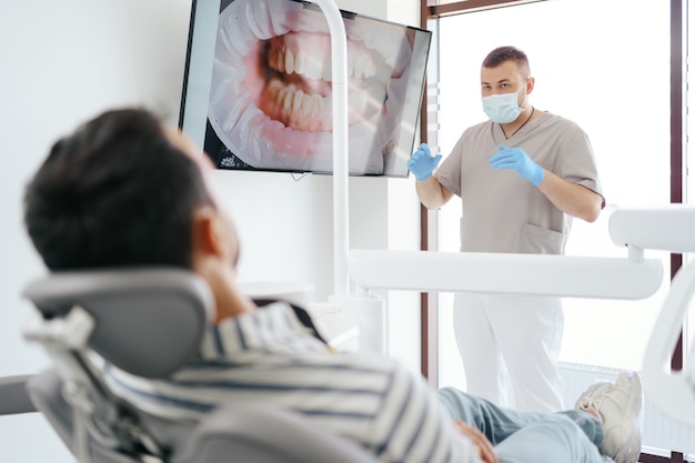 Zahnarzt im Gespräch mit dem Patienten, der das Bild seiner Zähne auf dem Bildschirm zeigt