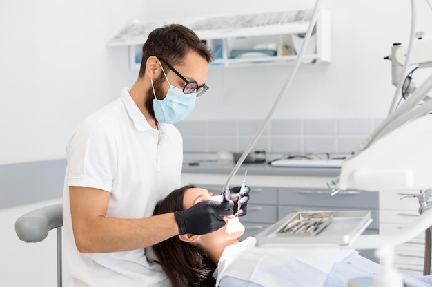 Zahnarzt mit Brille, der einer weiblichen Patientin Zähne füllt