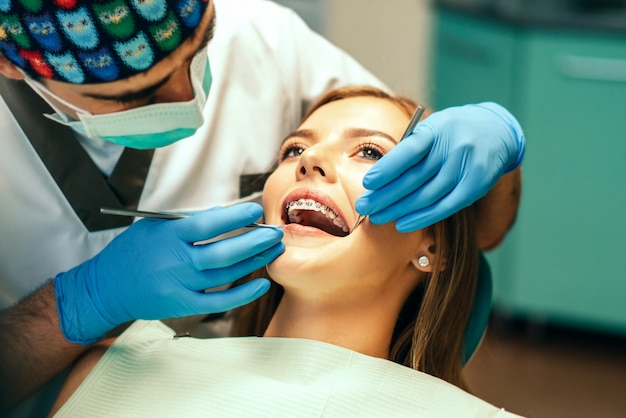 Zahnarzt überprüfen weiblichen Patienten mit Klammern im Denal-Büro.