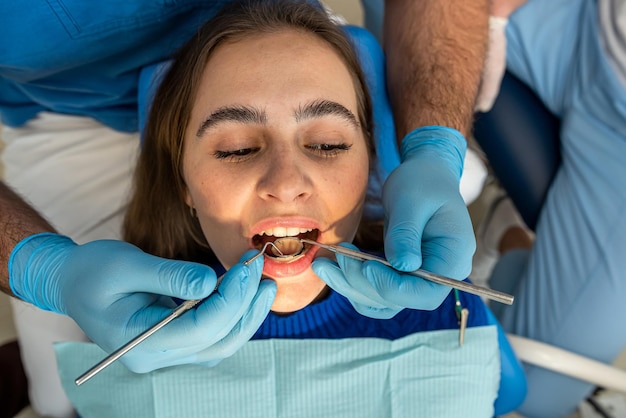 Zahnarzt und Assistentin in Maske behandelt Zähne Patientin in der Zahnarztpraxis Stomatologie