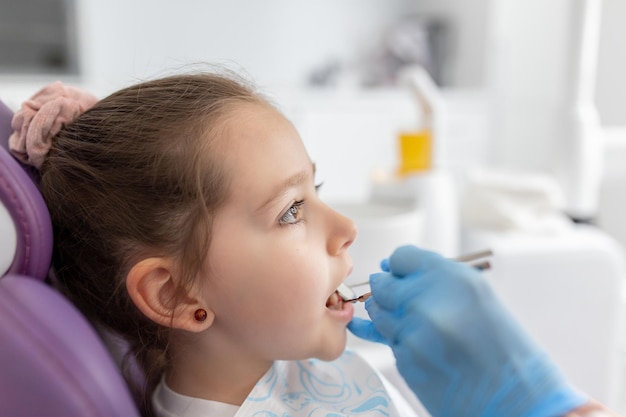 Zahnarzt untersucht die Zähne des kleinen Mädchens in der Klinik