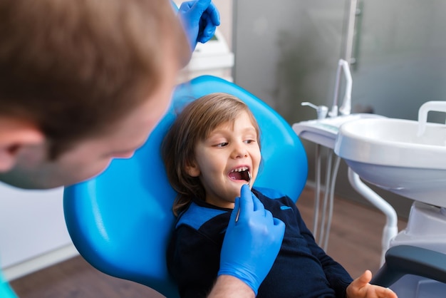 Zahnarzt untersucht die Zähne kleiner Jungen in der Klinik