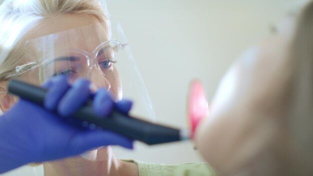 Foto zahnarzt verwendet zahnärztliches polymerisationslicht für die mundhöhle. professionelle zahnfüllung