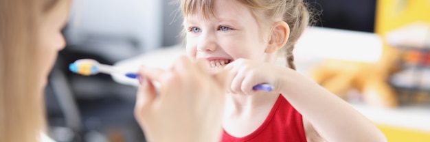 Zahnarzt zeigt Mädchen, wie man sich richtig die Zähne putzt