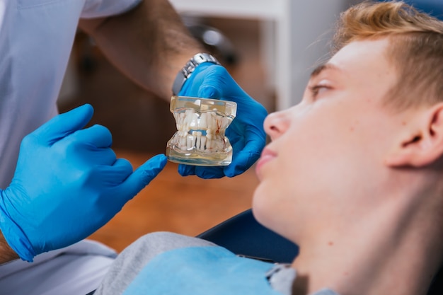Zahnarzt zeigt seinem Patienten einen Zahnersatz.