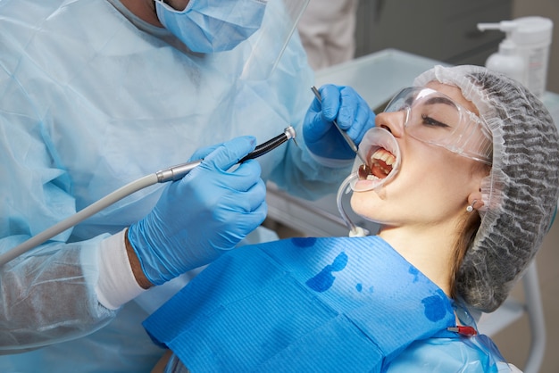 Zahnarztbohrzahn zum männlichen Patienten im Zahnarztstuhl