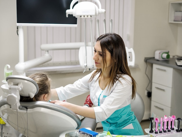 Zahnarztfrau, die Patientin des kleinen Mädchens für die Behandlung in der Zahnklinik vorbereitet.