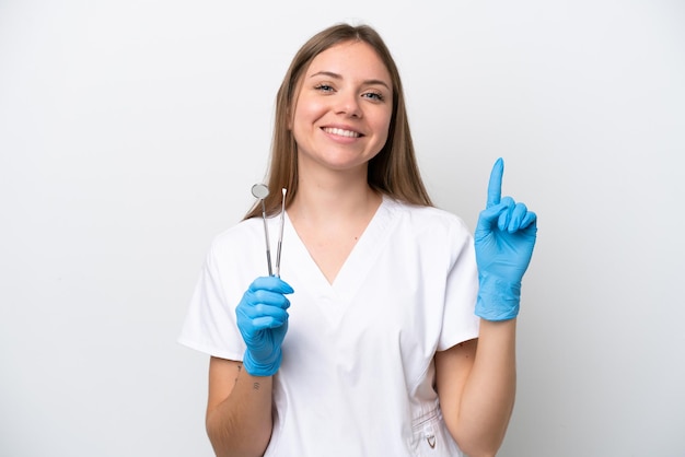 Zahnarztfrau, die Werkzeuge isoliert auf weißem Hintergrund hält und einen Finger im Zeichen der Besten zeigt und hebt