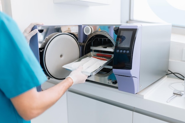 Foto zahnarzthelferin führt zahnarztgeräte in die sterilisationsmaschine ein