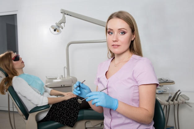 Zahnarztmädchen, das ein medizinisches Instrument vor dem Hintergrund einer Zahnarztpraxis hält