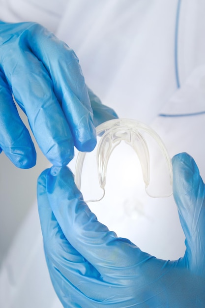 Zahnaufhellung eine Zahnform in der Hand des Arztes Zahnärztliche Schönheitsbehandlung Zähne, die Werkzeuge nach Zahnspangen halten Konzept Kieferorthopädie Zahnärztlicher Mundschutz jugendlich kieferorthopädisch