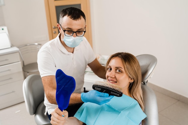 Zahnaufhellung Patient, der sich die Farbtöne der Zähne ansieht Zahnmedizin Arzt überprüft die passenden Proben der Zahnfarbe in der Zahnklinik