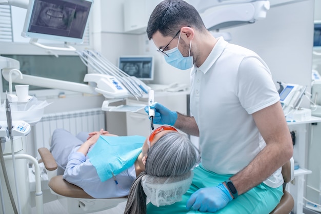 Zahnbehandlung. Patientin in Schutzbrille mit einer Zahnrestauration in der Zahnarztpraxis