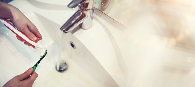 Zahnbürste und Paste mit Spiegelhintergrund im Badezimmer Nahaufnahme von Zahnpasta und Zahnbürste Hände drücken Aufhellungspaste auf die Bürste und kümmern sich um die Mundhygiene