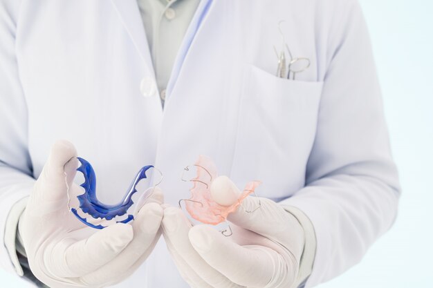 Zahnmedizinisches orthodontisches Gerät des Zahnarzthalters auf seiner Hand.