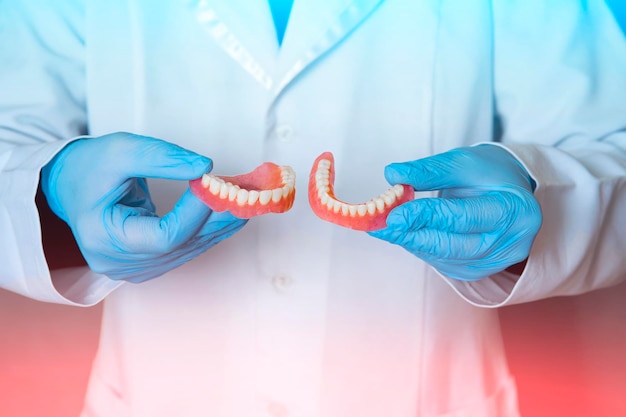 Zahnprothese in den Händen des Arztes Nahaufnahme Zahnarzt mit keramischer Zahnbrücke Vorderansicht der Vollprothese Zahnmedizin Konzeptfoto Prothetische Zahnheilkunde