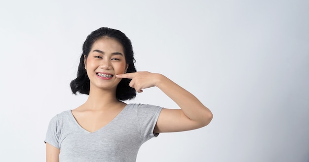 Zahnspangen der jugendlich asiatischen Frau, die Zahnspangenzähne und Kontaktlinsen trägt sie sehr selbstbewusst und stolz präsentieren sich und lächeln auf weißer Wand Glück Teenager lächelnd