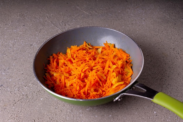 La zanahoria frita se encuentra en una sartén sobre un fondo gris