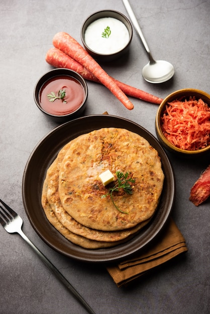 La zanahoria o gajar ka paratha es un plato punjabi que es un pan plano sin levadura indio hecho con harina de trigo integral y zanahoria. Servido con salsa de tomate y cuajada.