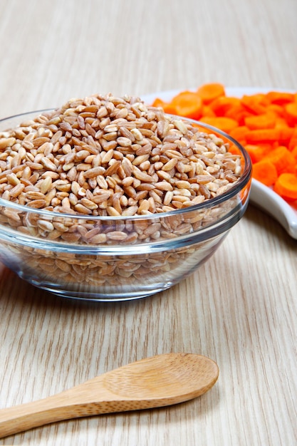 Foto zanahorias y espelta seca en un cuenco en una mesa