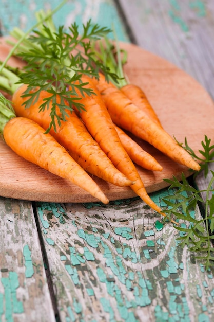 Foto zanahorias frescas y crujientes con verduras en una tabla de madera