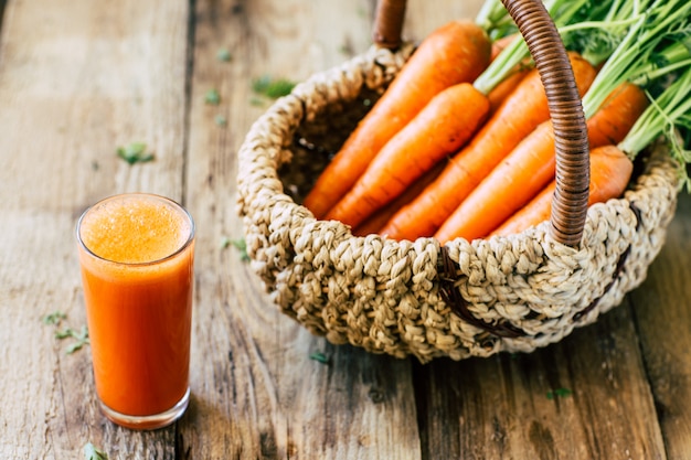 Zanahorias frescas maduras y jugo en madera