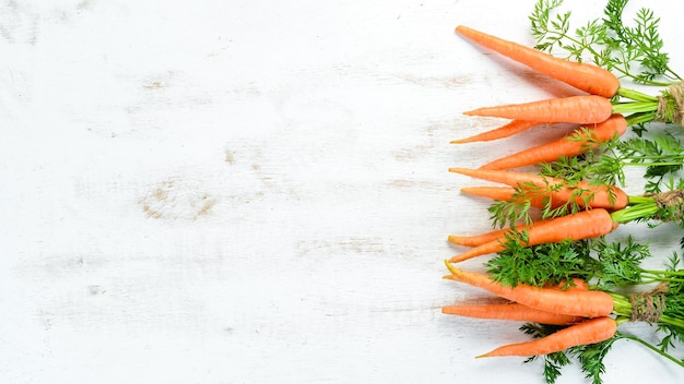 Zanahorias frescas sobre un fondo blanco de madera Vista superior Espacio libre para su texto